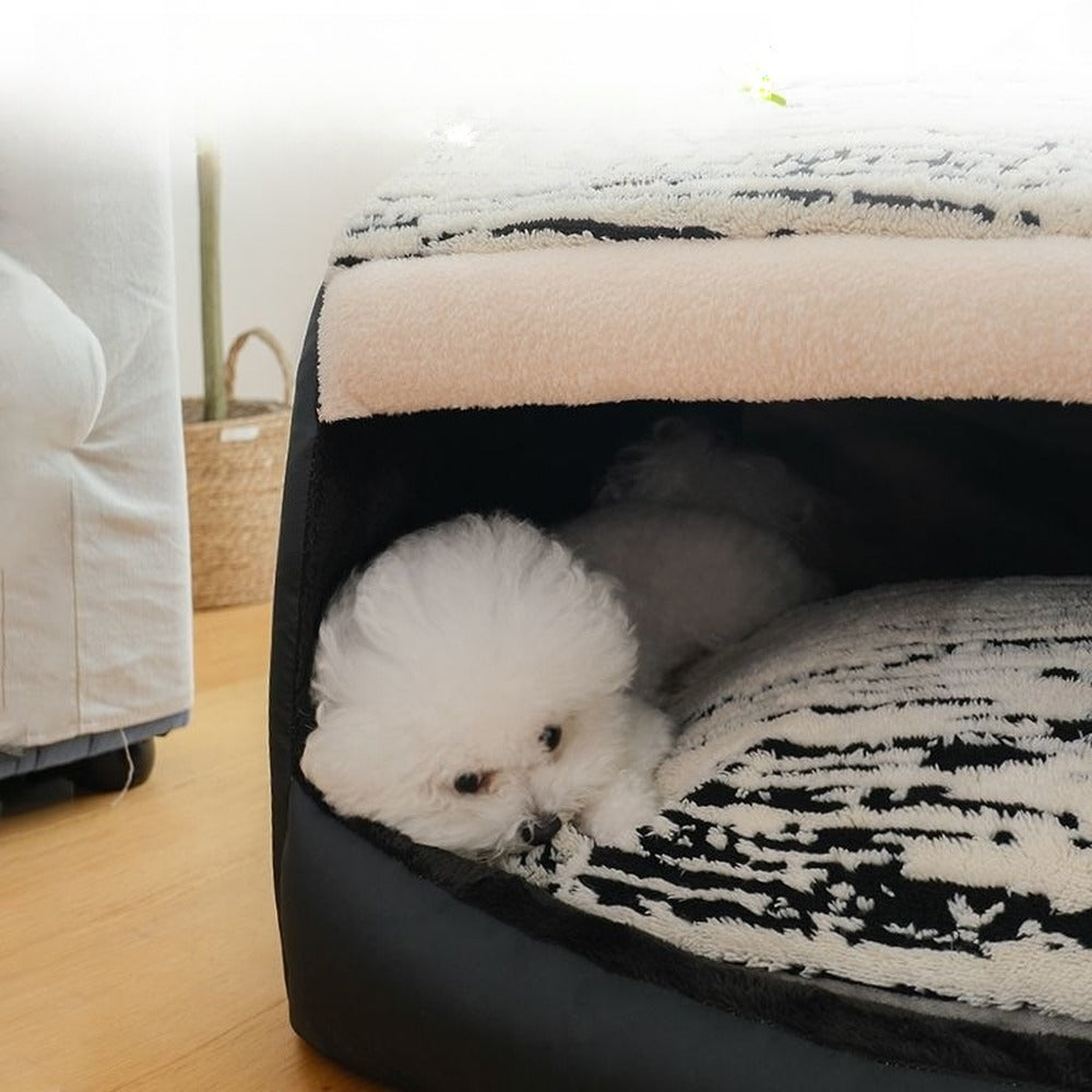 Small dog sleeping inside covered pet bed