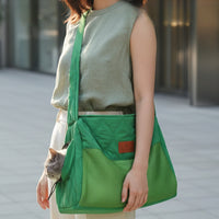 Woman carrying cat in green mesh shoulder carrier