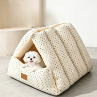 Small white dog hiding inside a cream corduroy cat cave bed